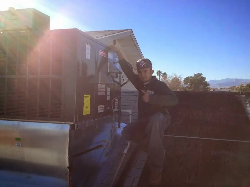 HVAC technician performing AC Tune-Up on a rooftop unit in North Salt Lake